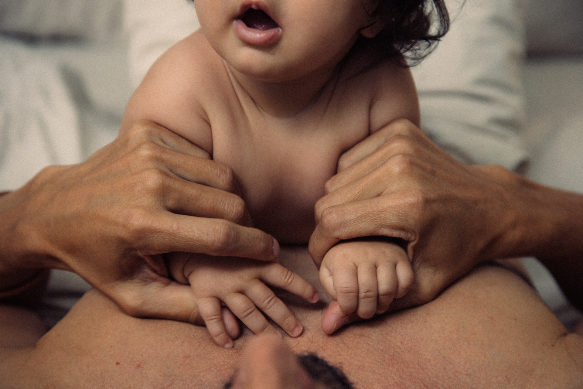 Close-up of a baby's hands held by an adult's hands, with a blurred background.